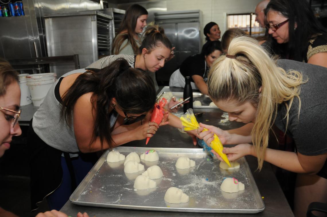 a group of young women decorating mexican bread