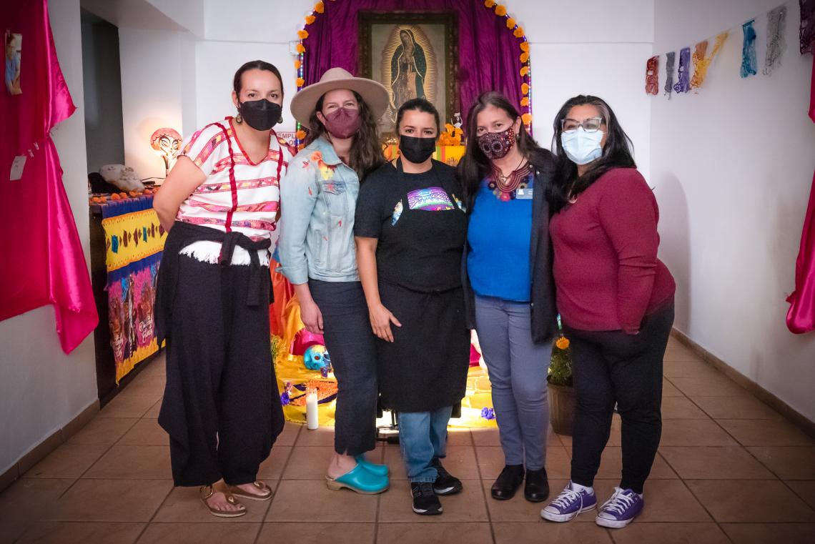 a group of women standing in front of a dia de los muertos alter